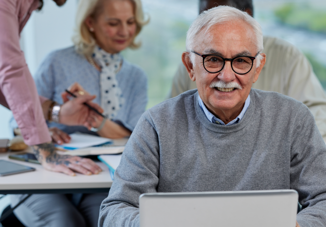 Older man learning to use a computer in class environment
